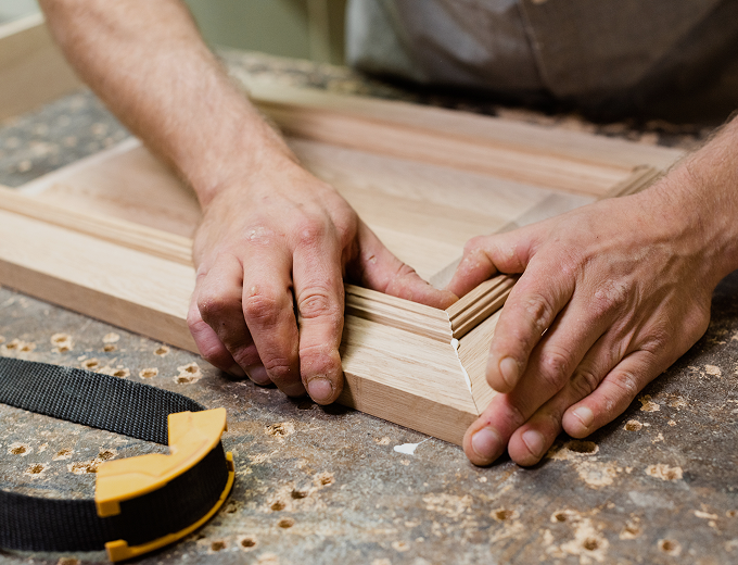 Woodworker assembling wooden frame with hands