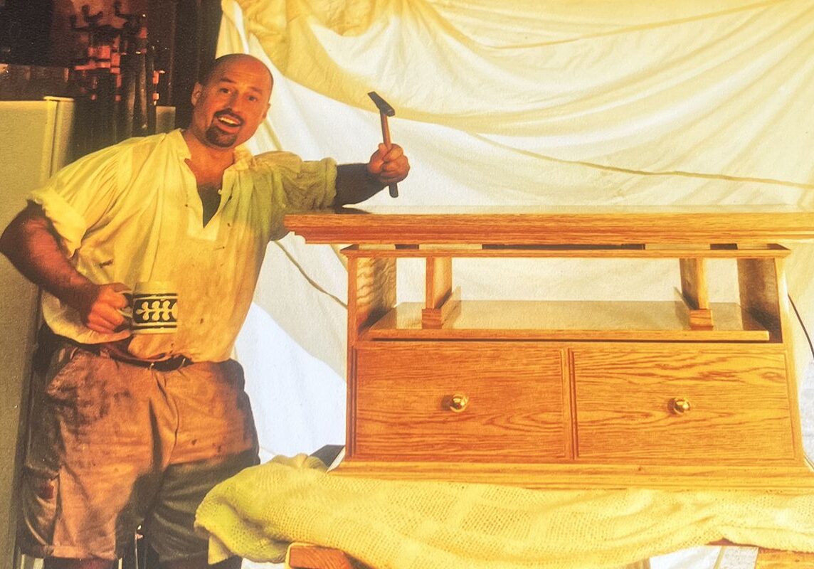 Man with wooden furniture and mug.